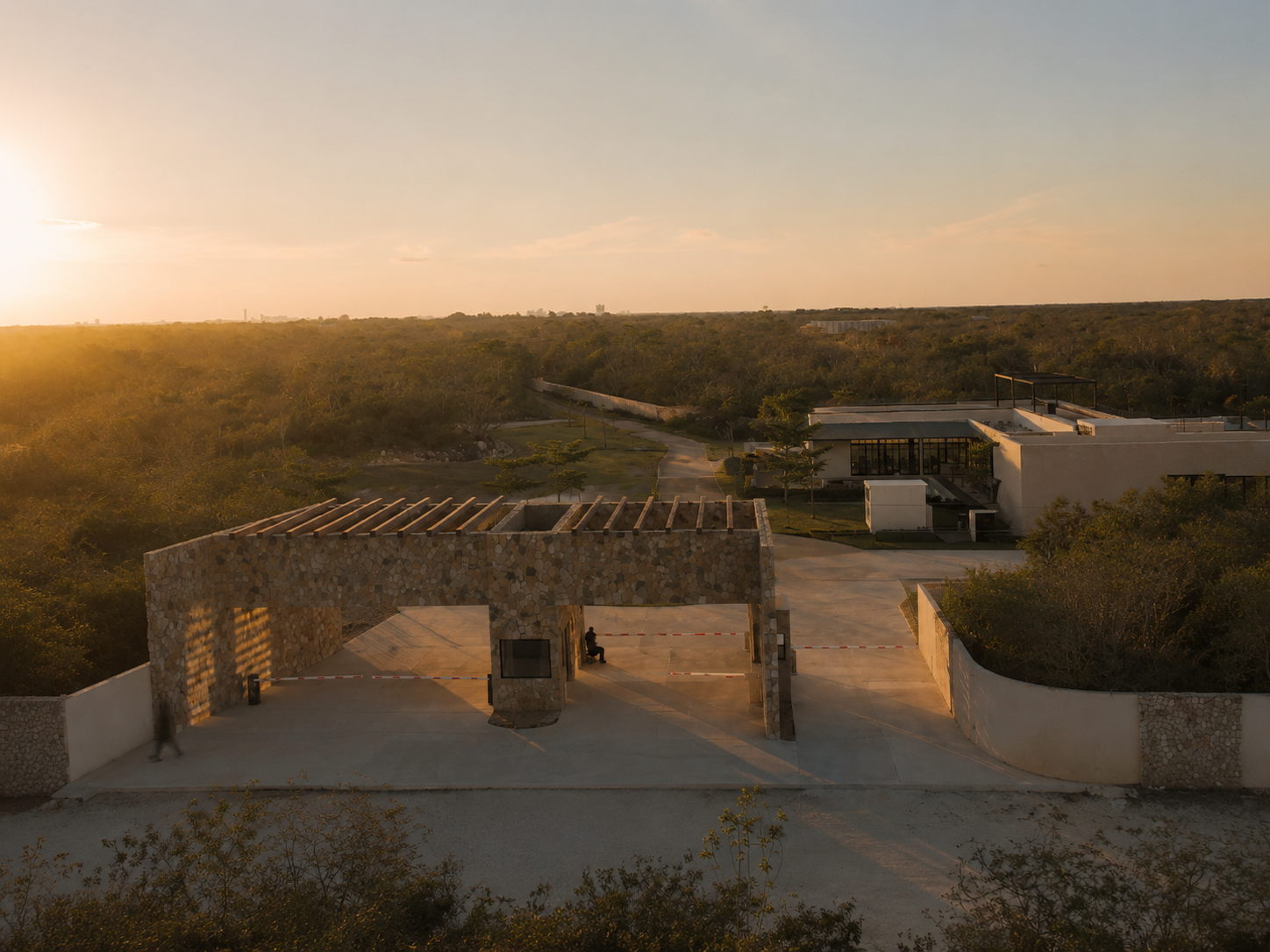 Acceso de piedra de Salama al atardecer, con la casa club al fondo y la naturaleza yucateca