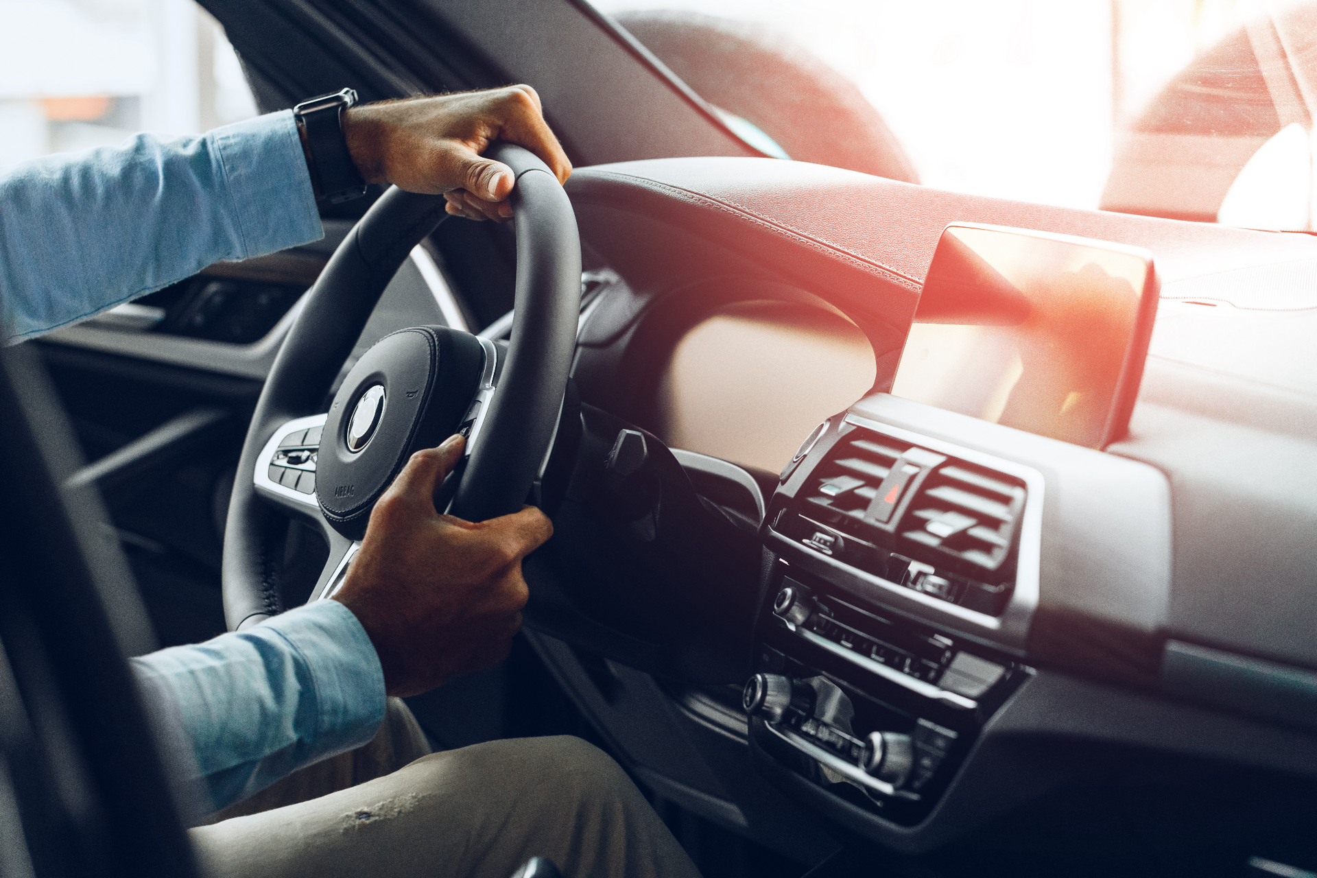 Closeup of hands holding a car steering wheel.