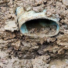 A muddy pipe is sitting in the middle of a pile of mud.