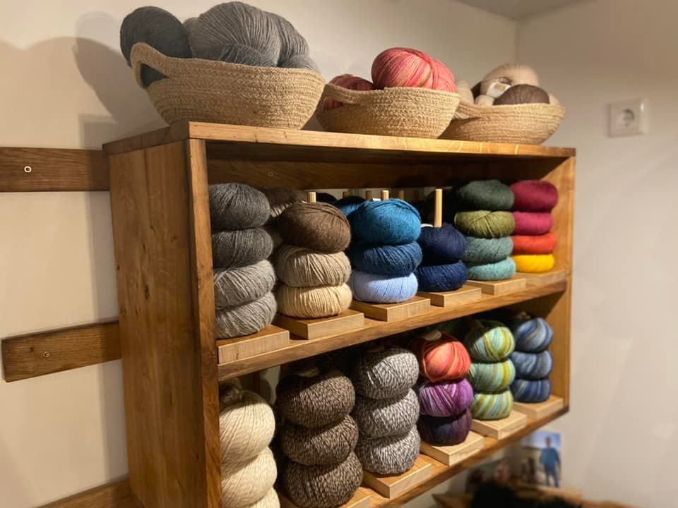 Ein Holzregal voller Wollknäuel und Körbe.