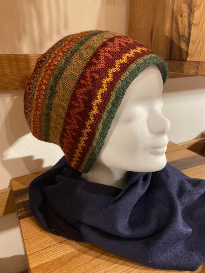 Eine Schaufensterpuppe mit Hut und Schal sitzt auf einem Holztisch.