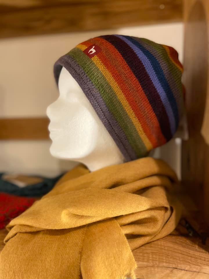 Eine Schaufensterpuppe, die eine Mütze und einen Schal mit Regenbogenstreifen trägt.