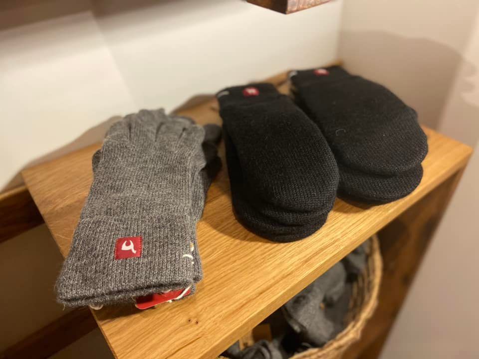 Zwei Paar Handschuhe liegen auf einem Holzregal.