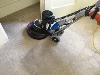 Carpet cleaner machine on beige carpet in a doorway, cleaning a circular section