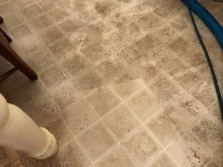 Beige tiled floor with a chair leg, white pipe, and blue hose visible at the edges