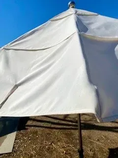 White tent canopy under a blue sky with a dirt ground below
