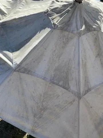 Close-up of a weathered gray metal roof with ridges and seams, showing a tent-like peaked structure
