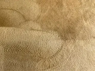 Close-up of a tan textured fabric surface with soft folds and shadows