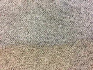 Close-up of a gray and beige speckled fabric or carpet surface with a horizontal seam line