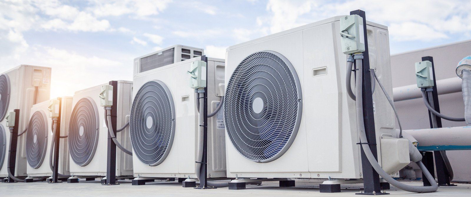 Two electricians working on an electrical panel outside a building. One holds a cable.