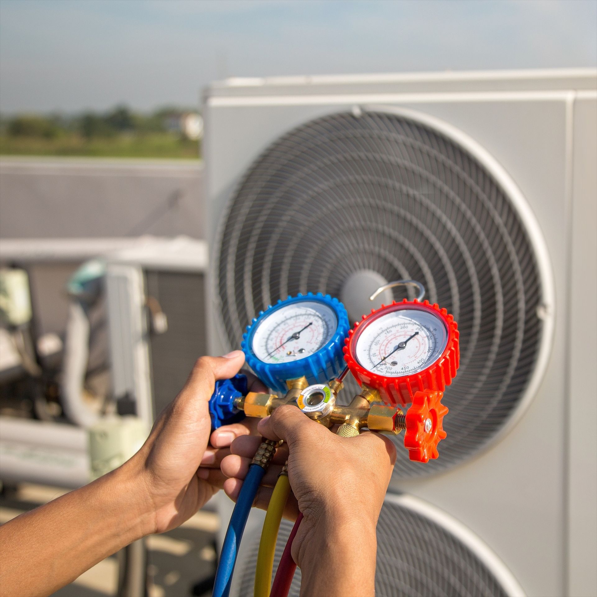 Two electricians working on an electrical panel outside a building. One holds a cable.
