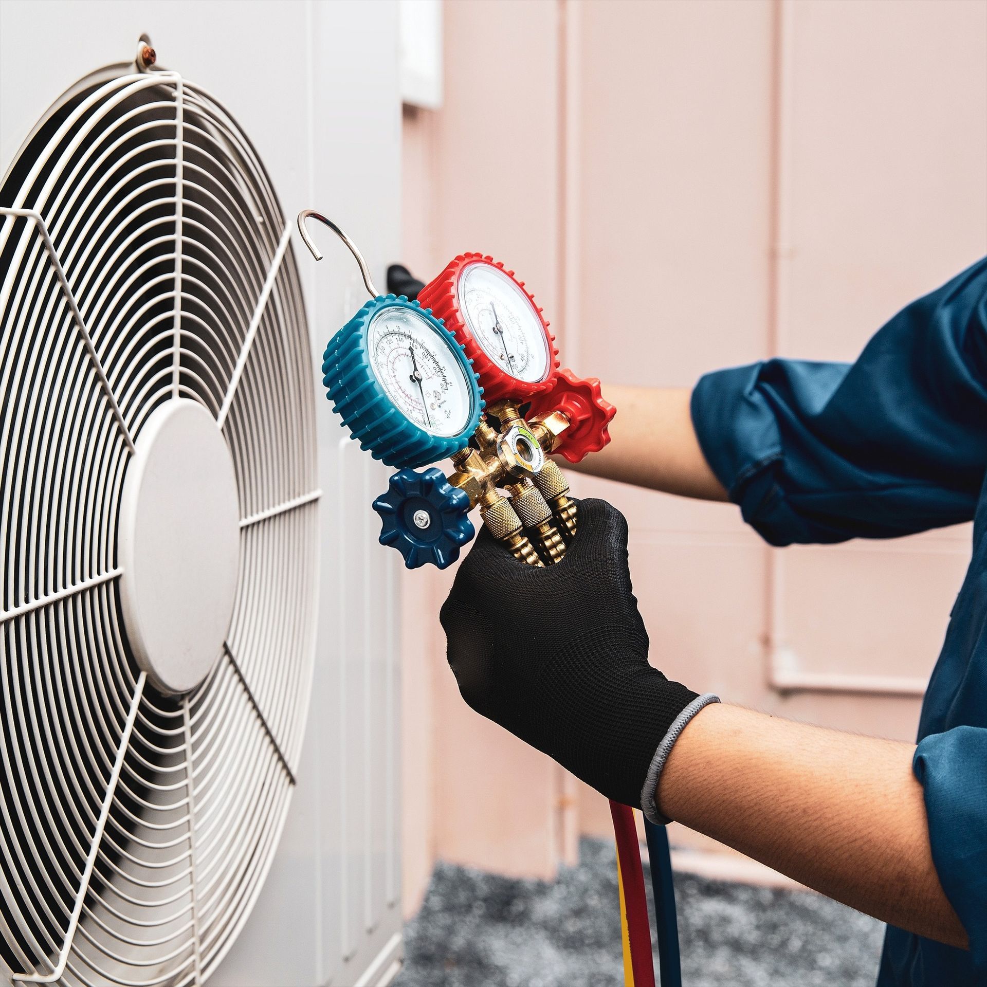 A person digs a trench in a backyard near a small excavator, a tree, and a house.