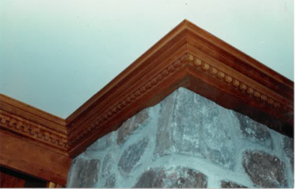 Brown wooden molding frames the corner of a stone wall, meeting the white ceiling.