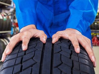 Mechanic Holding a Tire in Vehicle Shop — Wheel Alignments & New Tires in Biddeford, ME