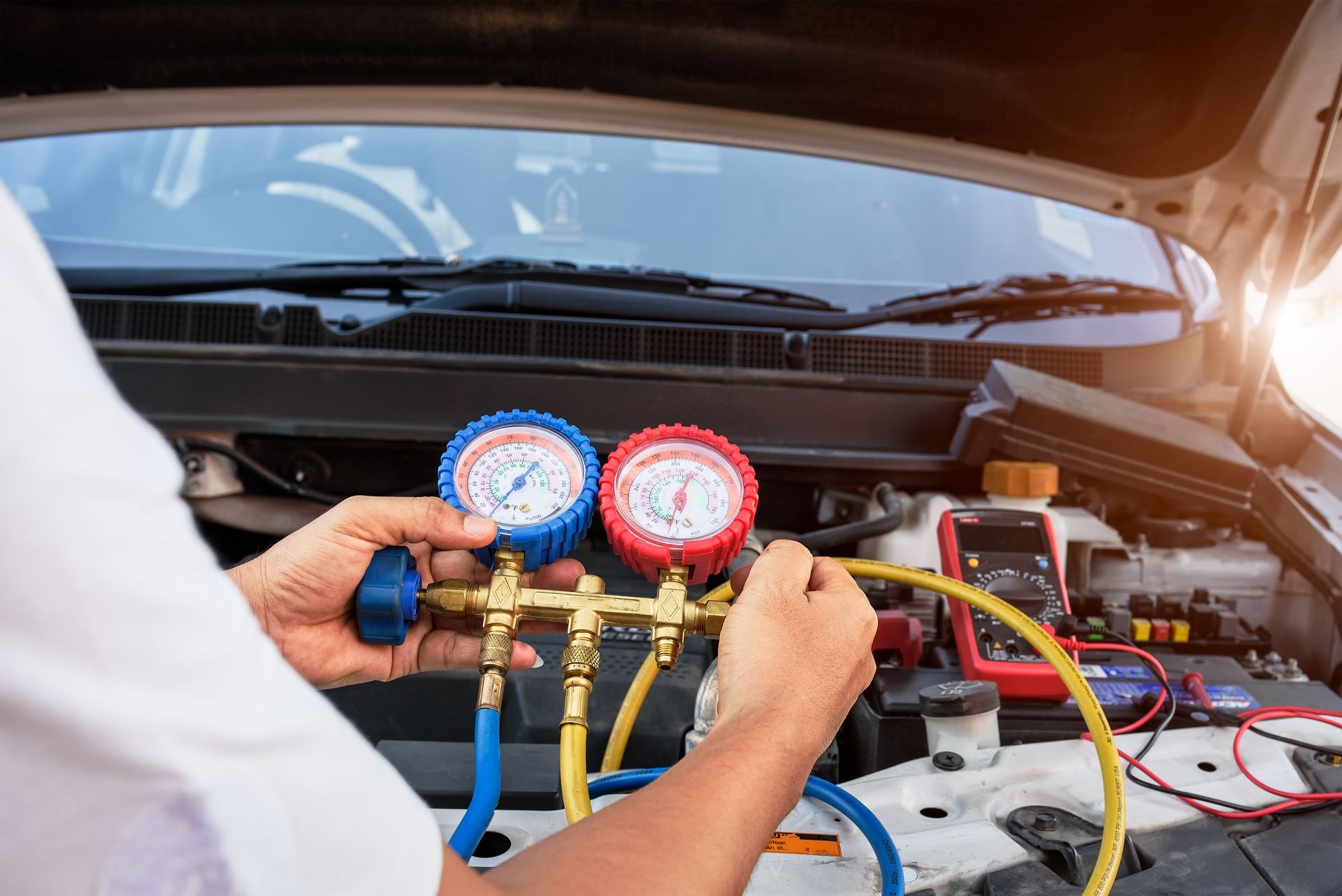 Technician performing Auto AC Repair in Sanford, ME, using pressure gauges to check the air conditio