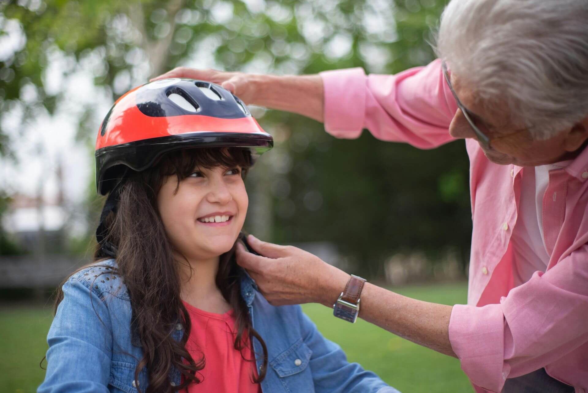 Parent putting a bicycle helmet on a girl