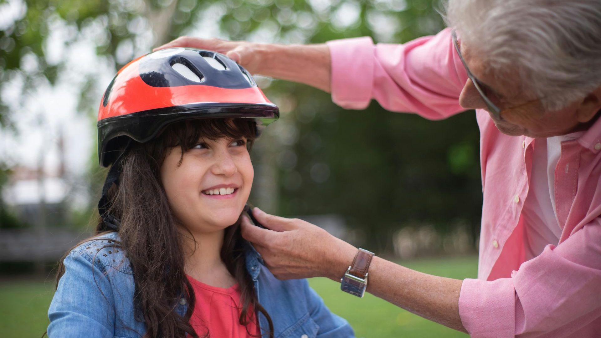 Parent putting a bicycle helmet on a girl