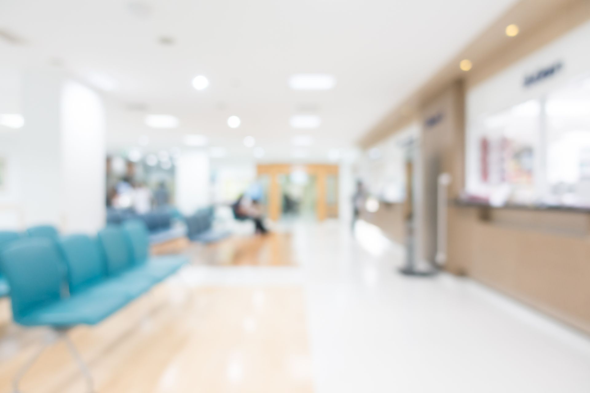 A blurry picture of a hospital waiting room with blue chairs.