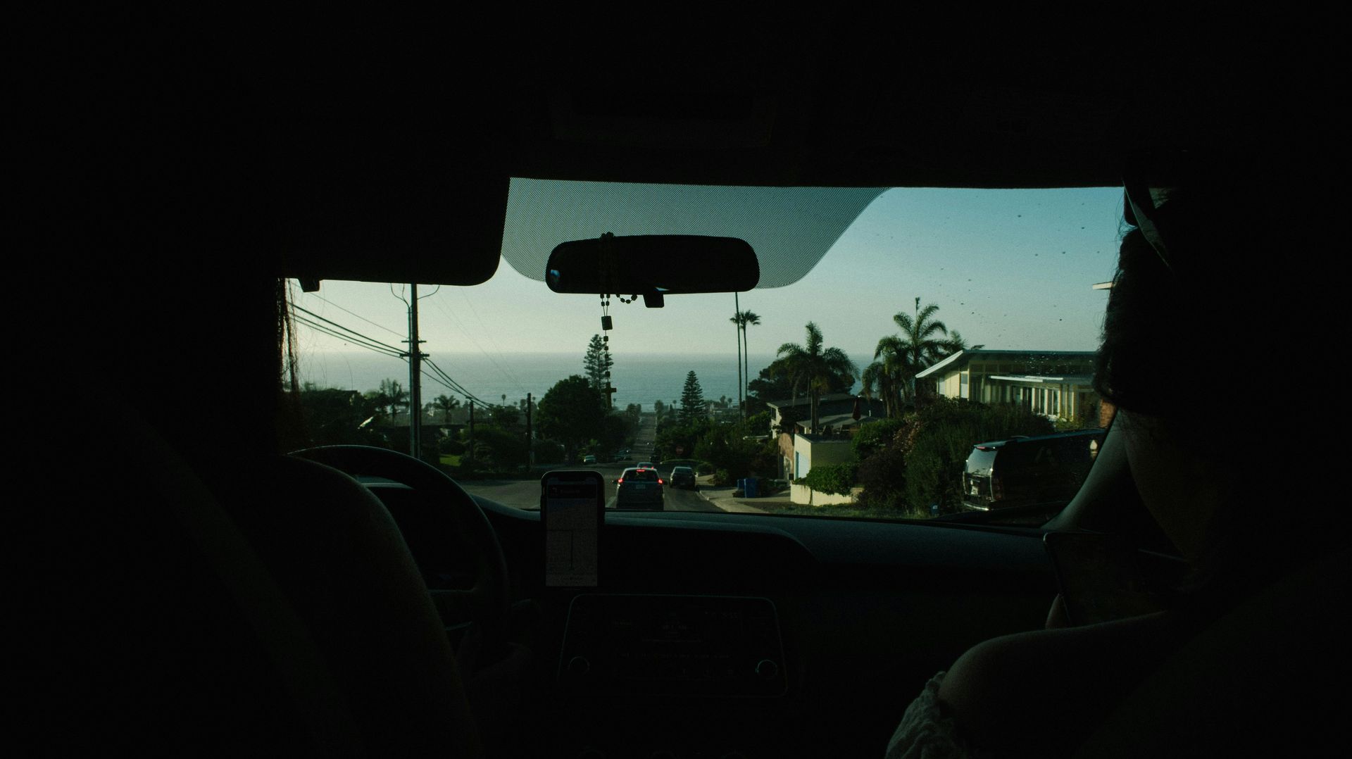 A person is driving a car and looking out the window at the ocean.