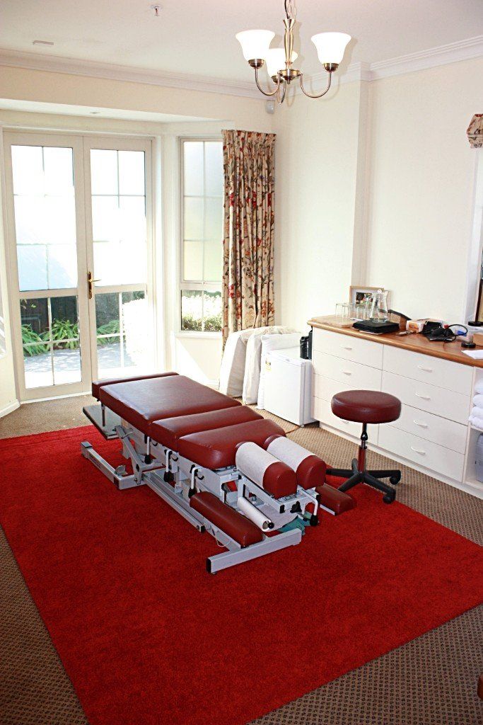 A room with a massage table and a red rug.