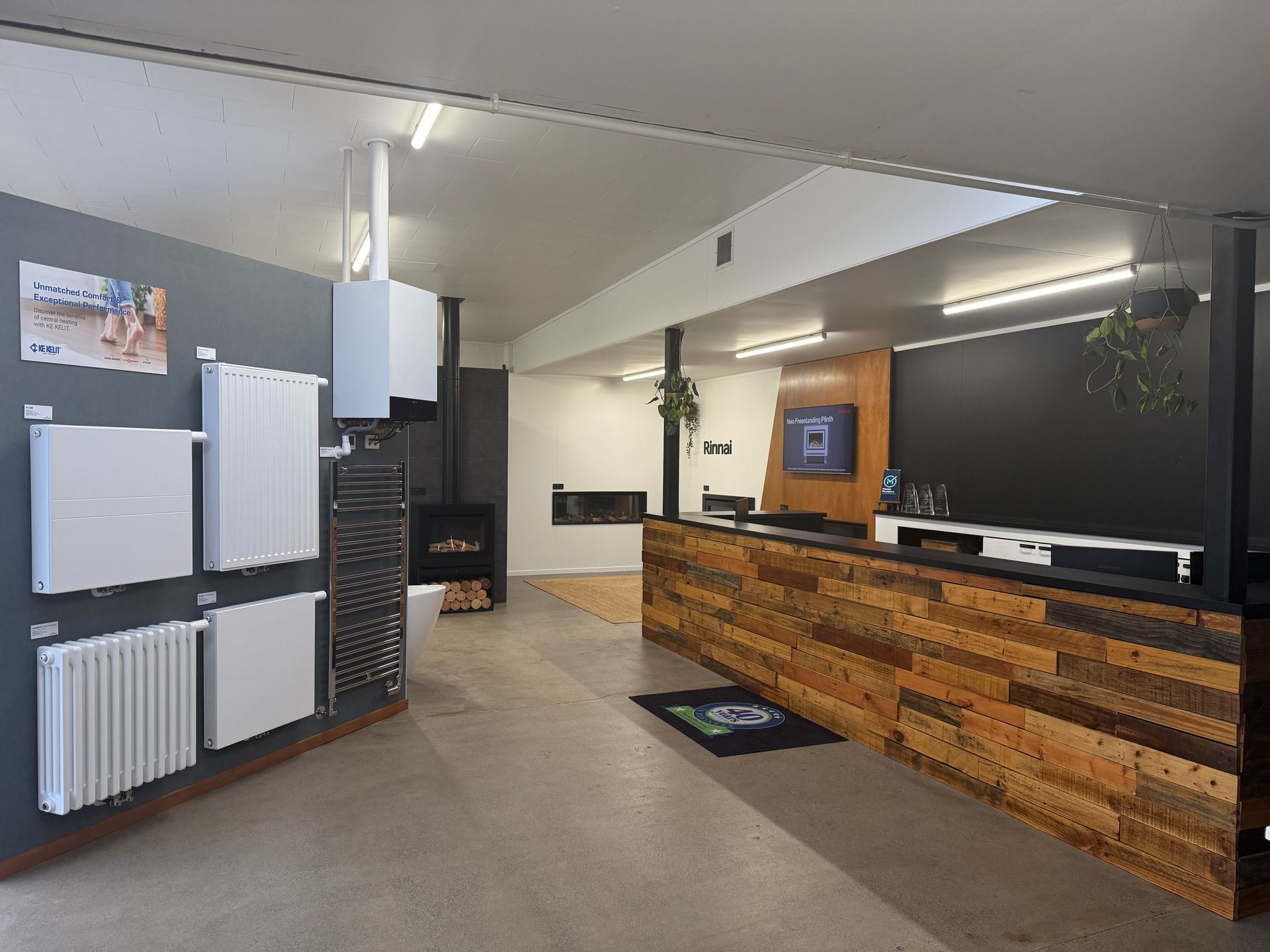 Showroom with heating appliances on display: radiators, a fireplace, and a counter.
