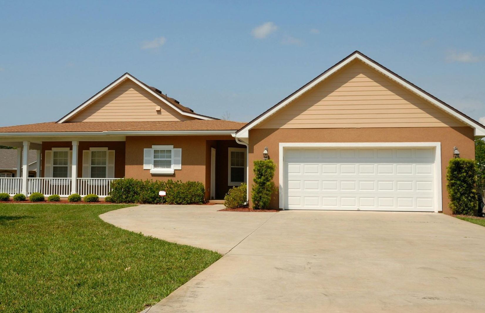 A large house with two garage doors and a concrete driveway.