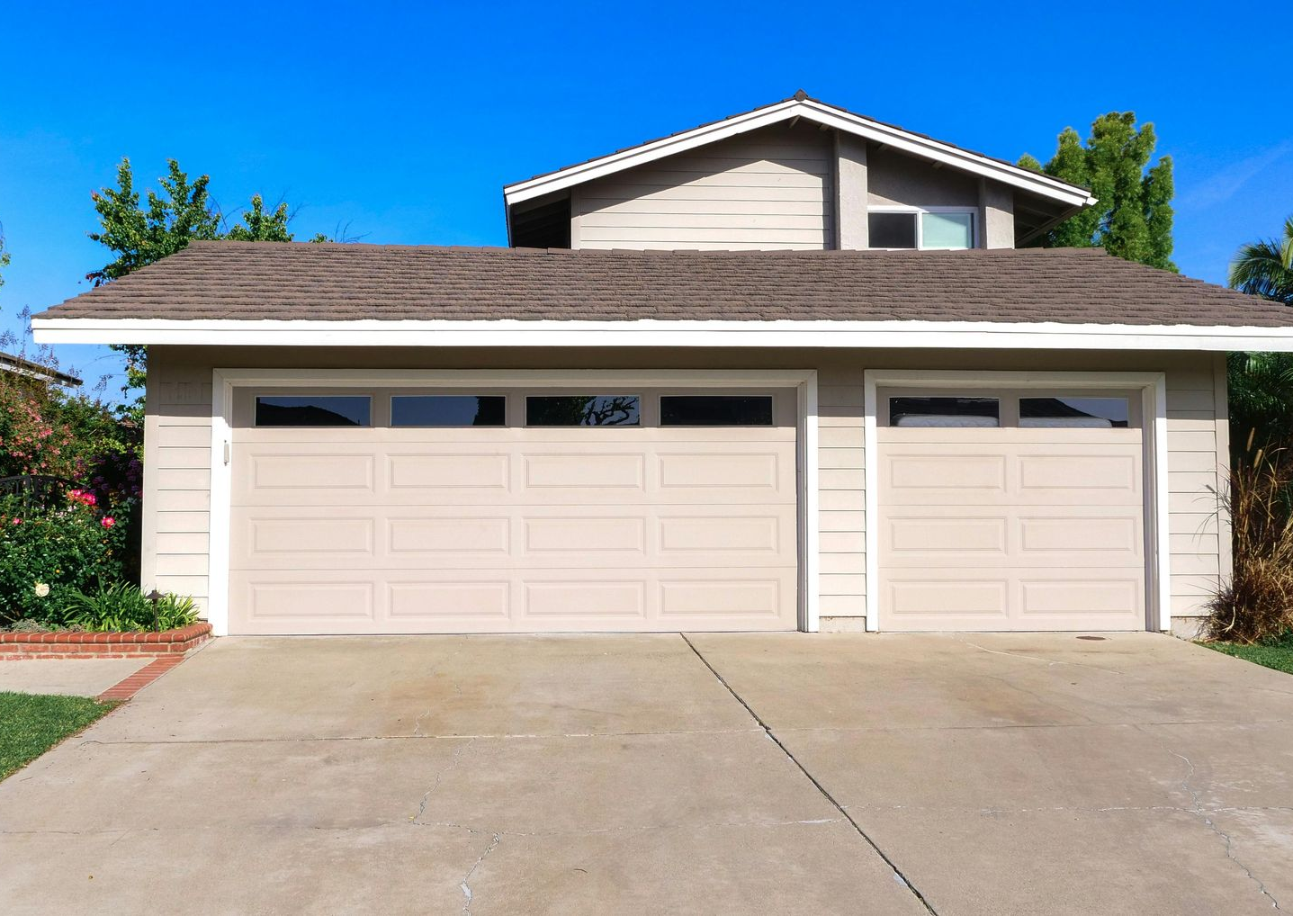 A large house with two garage doors and a concrete driveway.