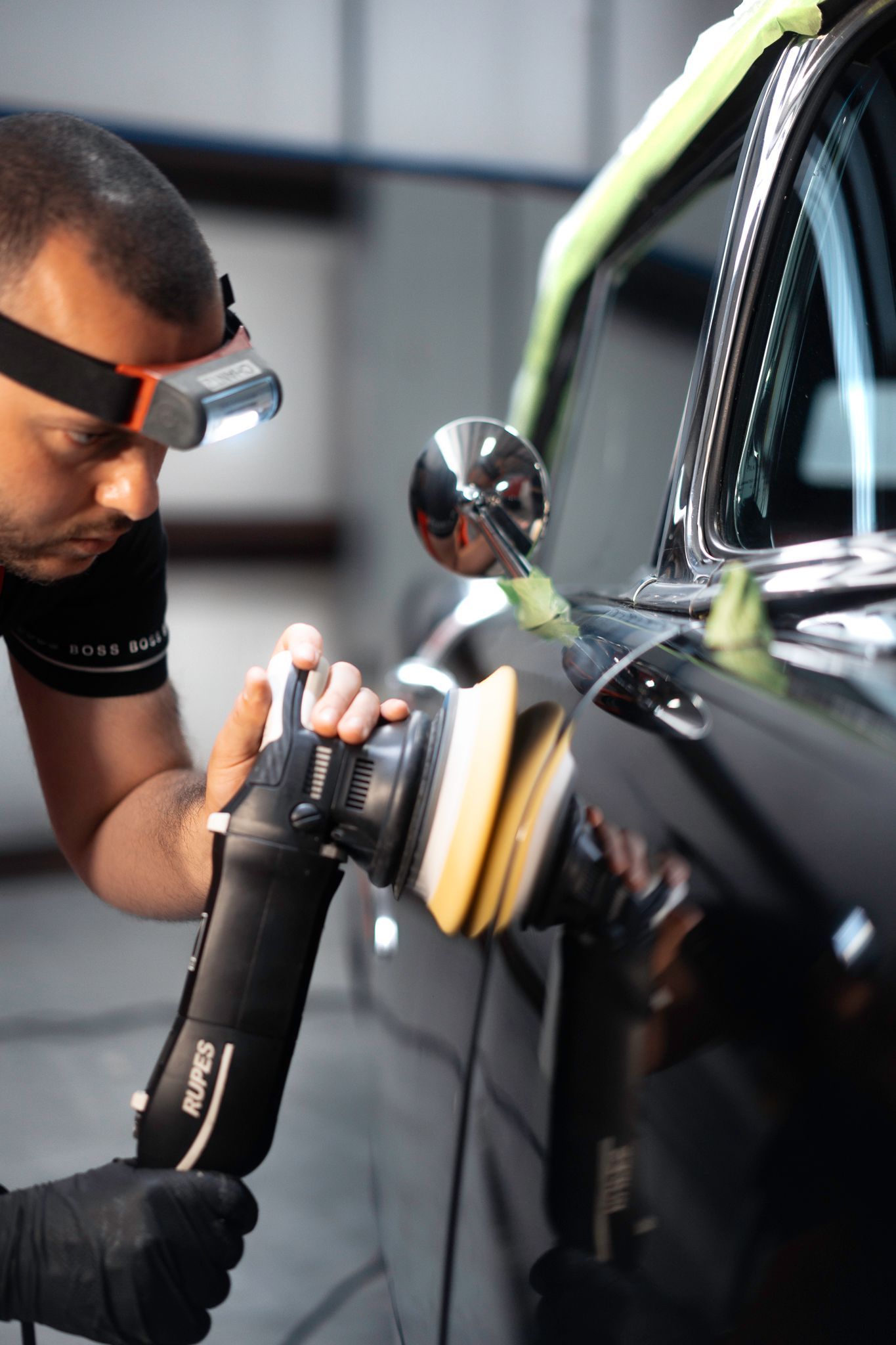 A man is polishing the front of a white sports car.