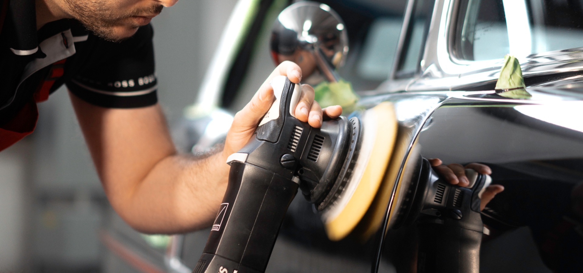 A man is polishing a car with a machine.