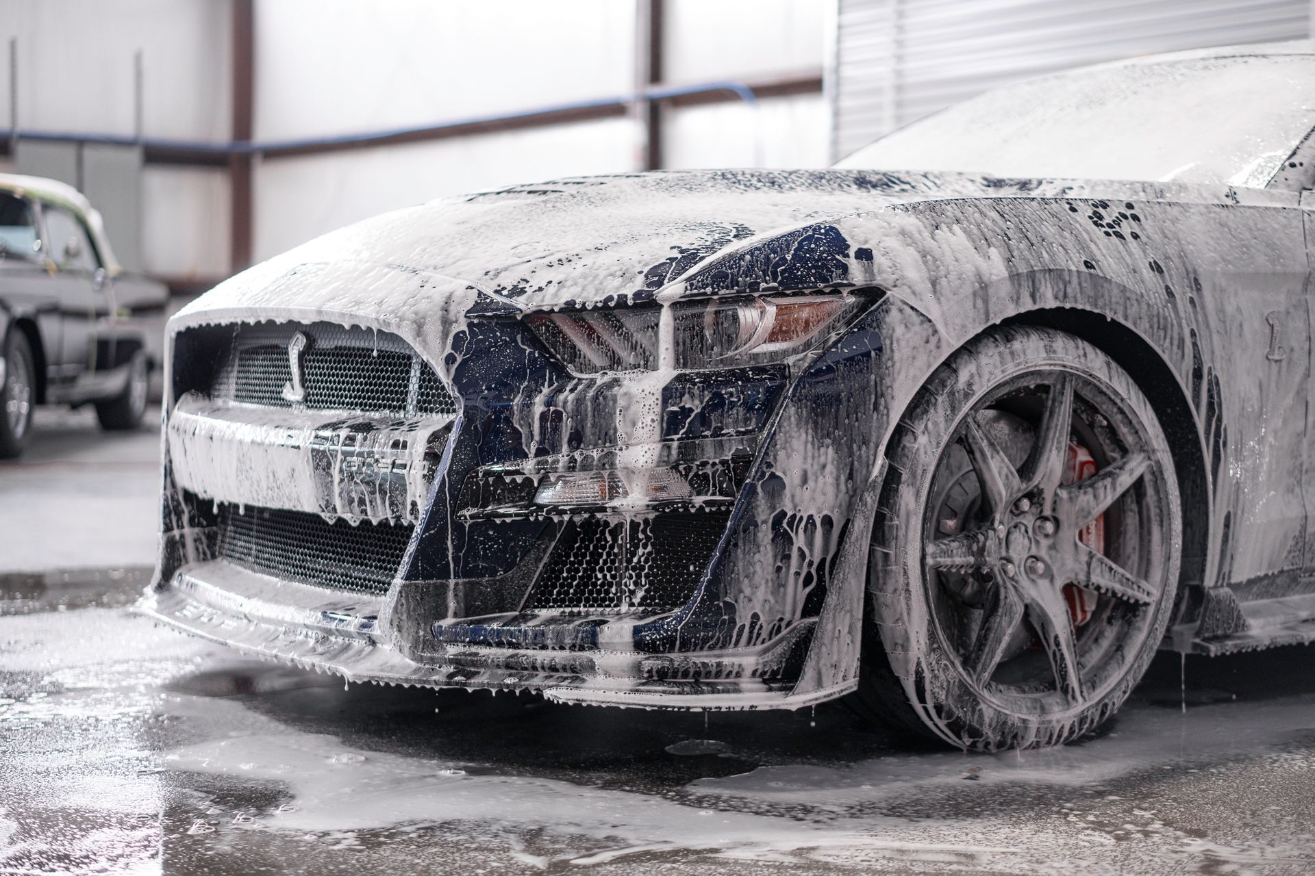 A red and black boat is parked in a garage.