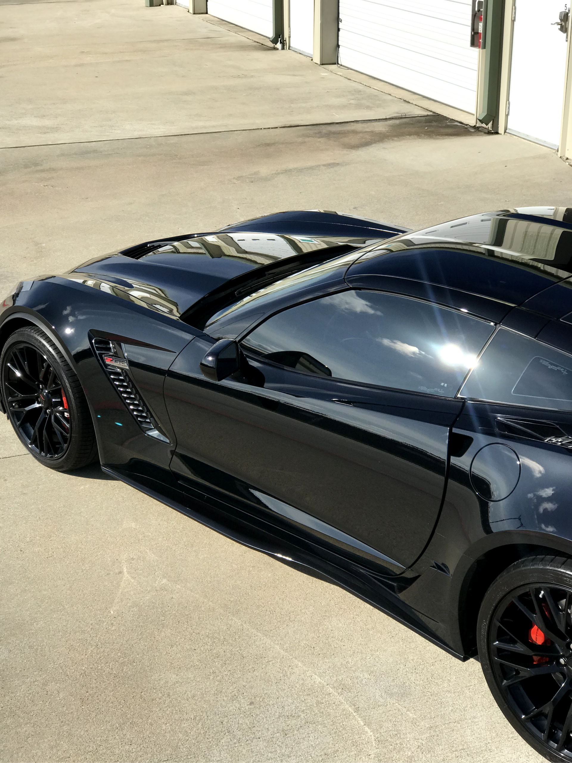 A black sports car is parked in front of a garage door
