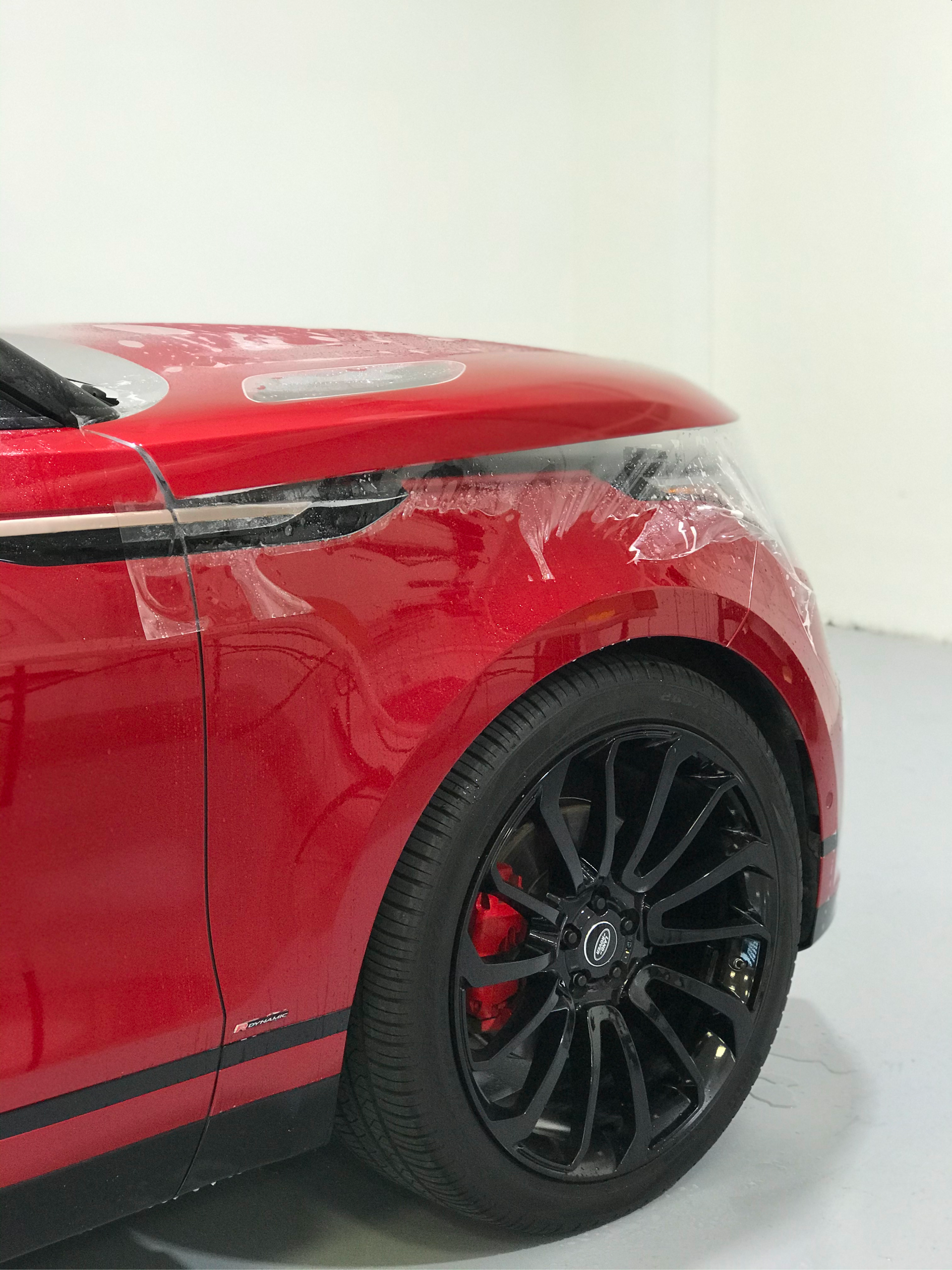 A red car with black wheels is parked in a garage