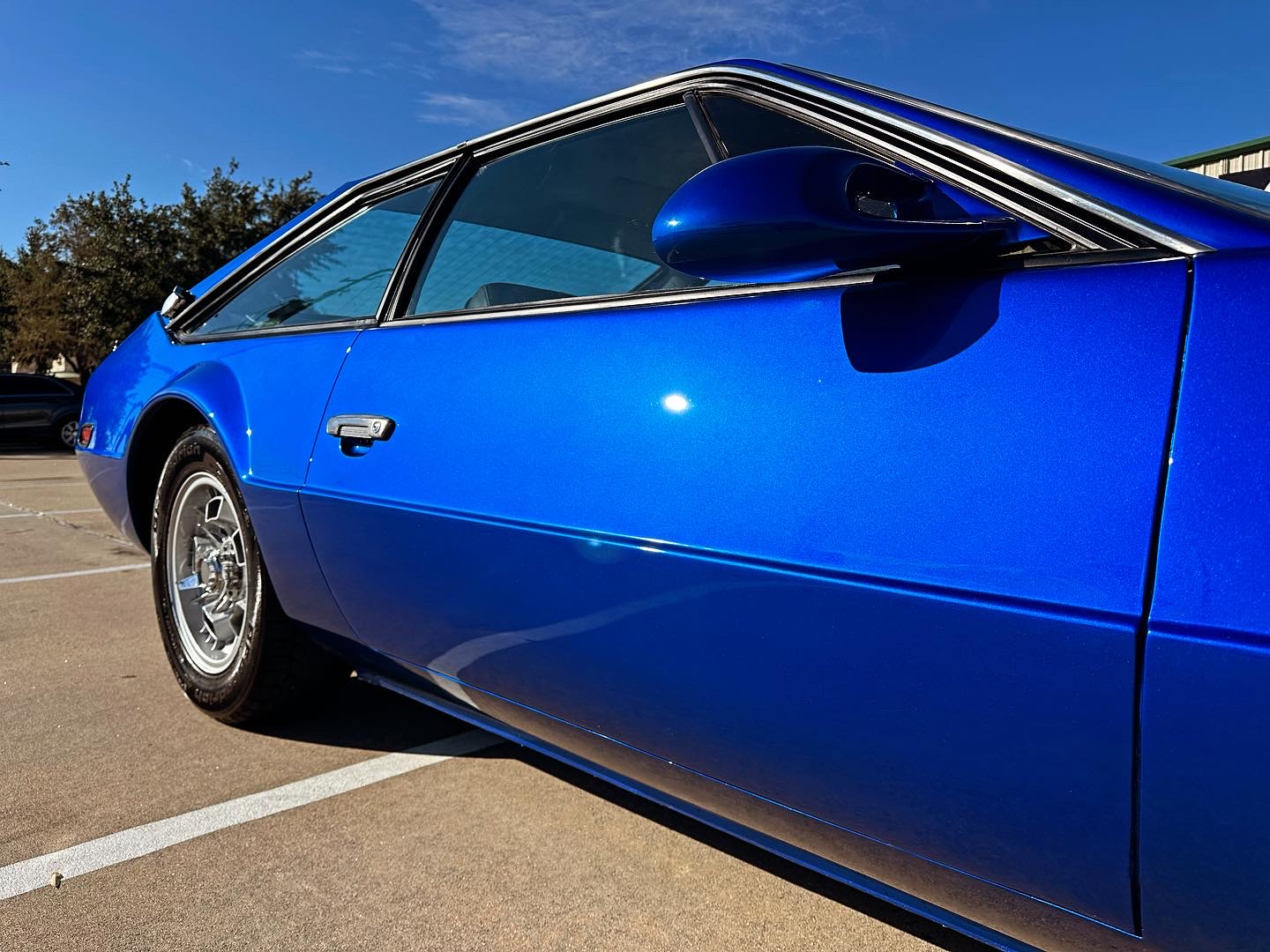A blue car is parked in a parking lot