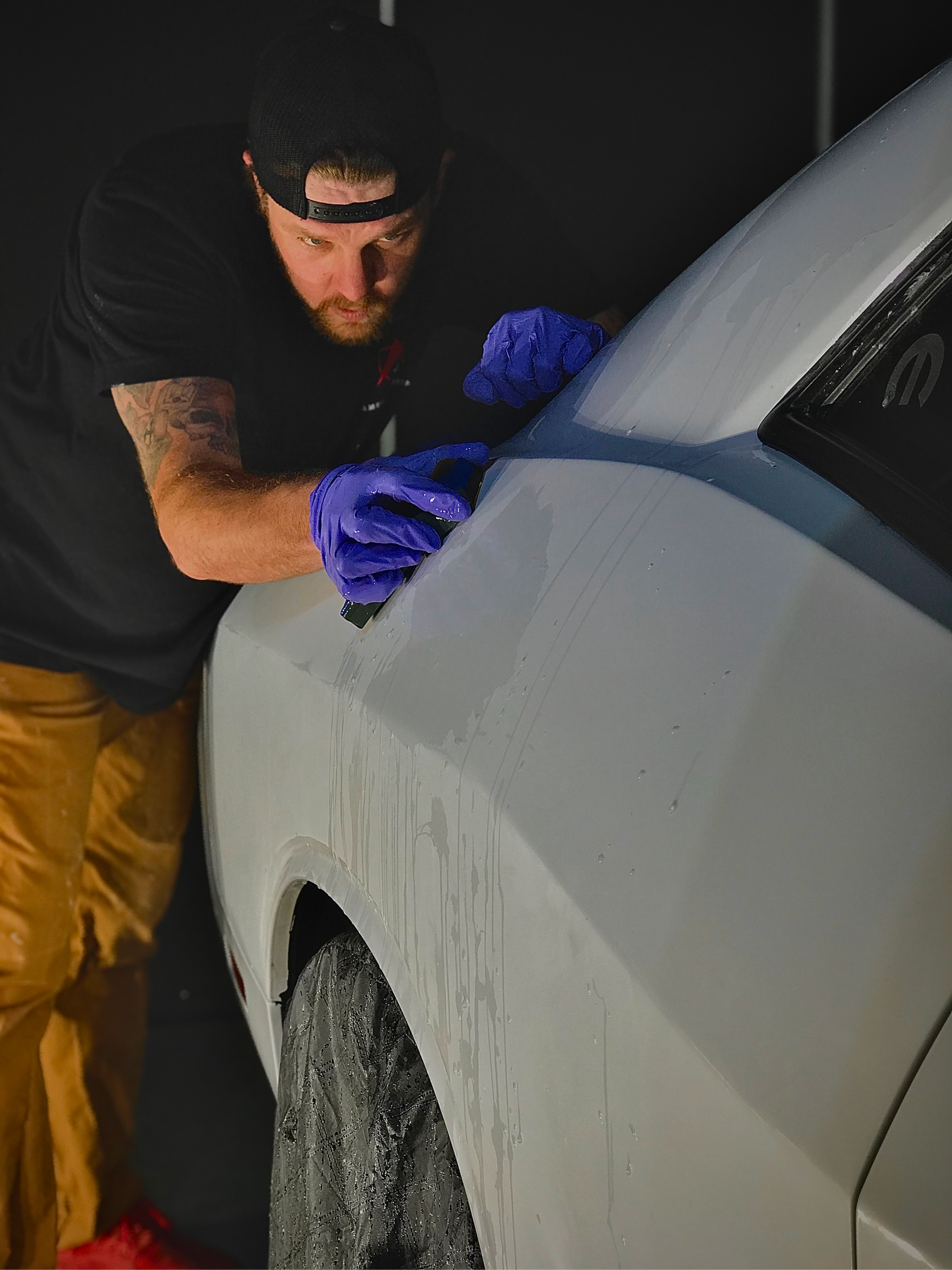 A man is cleaning the side of a car with a sponge.
