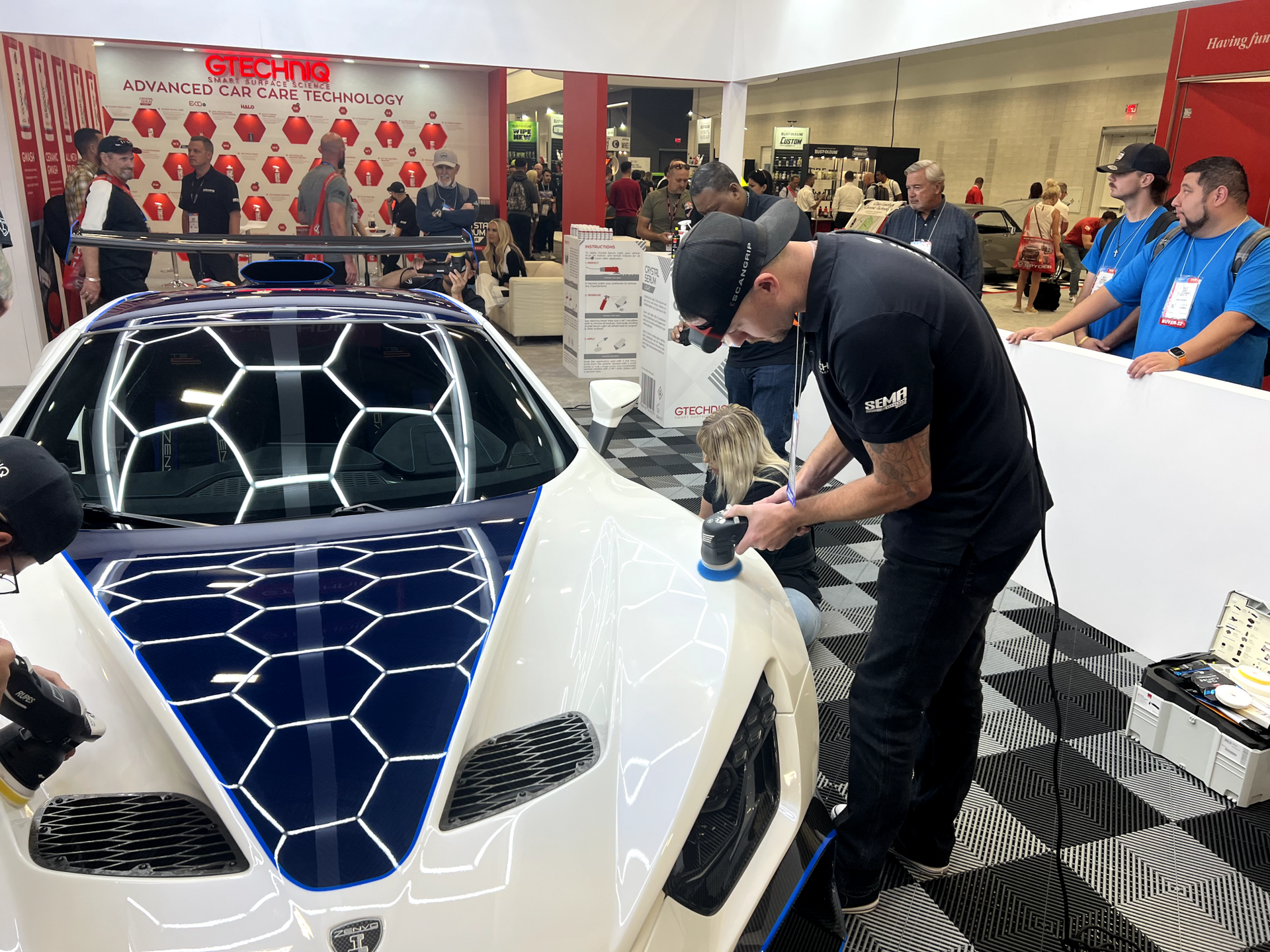A man is polishing the front of a white sports car.
