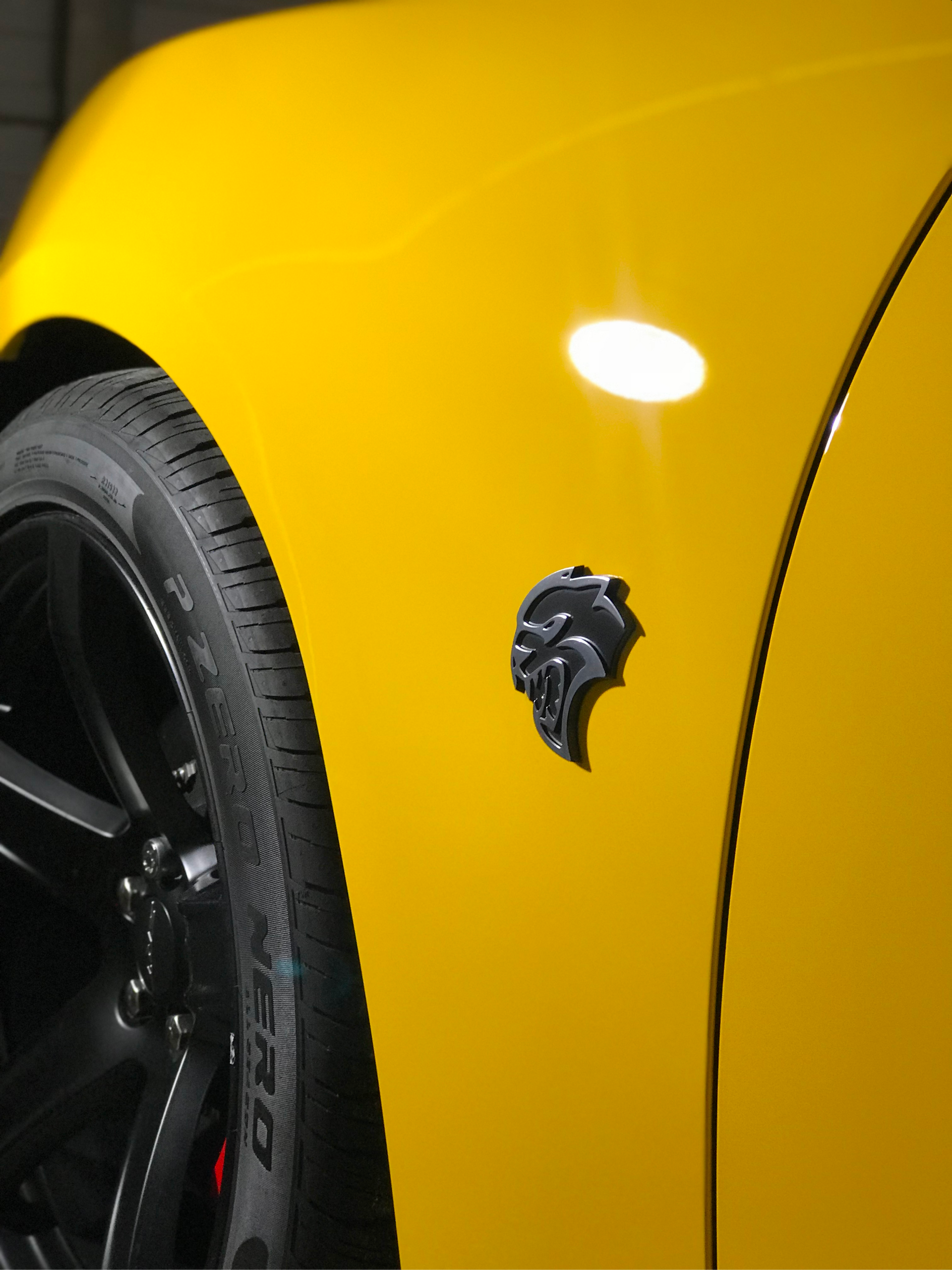 A close up of a yellow car with a tire that says pirelli