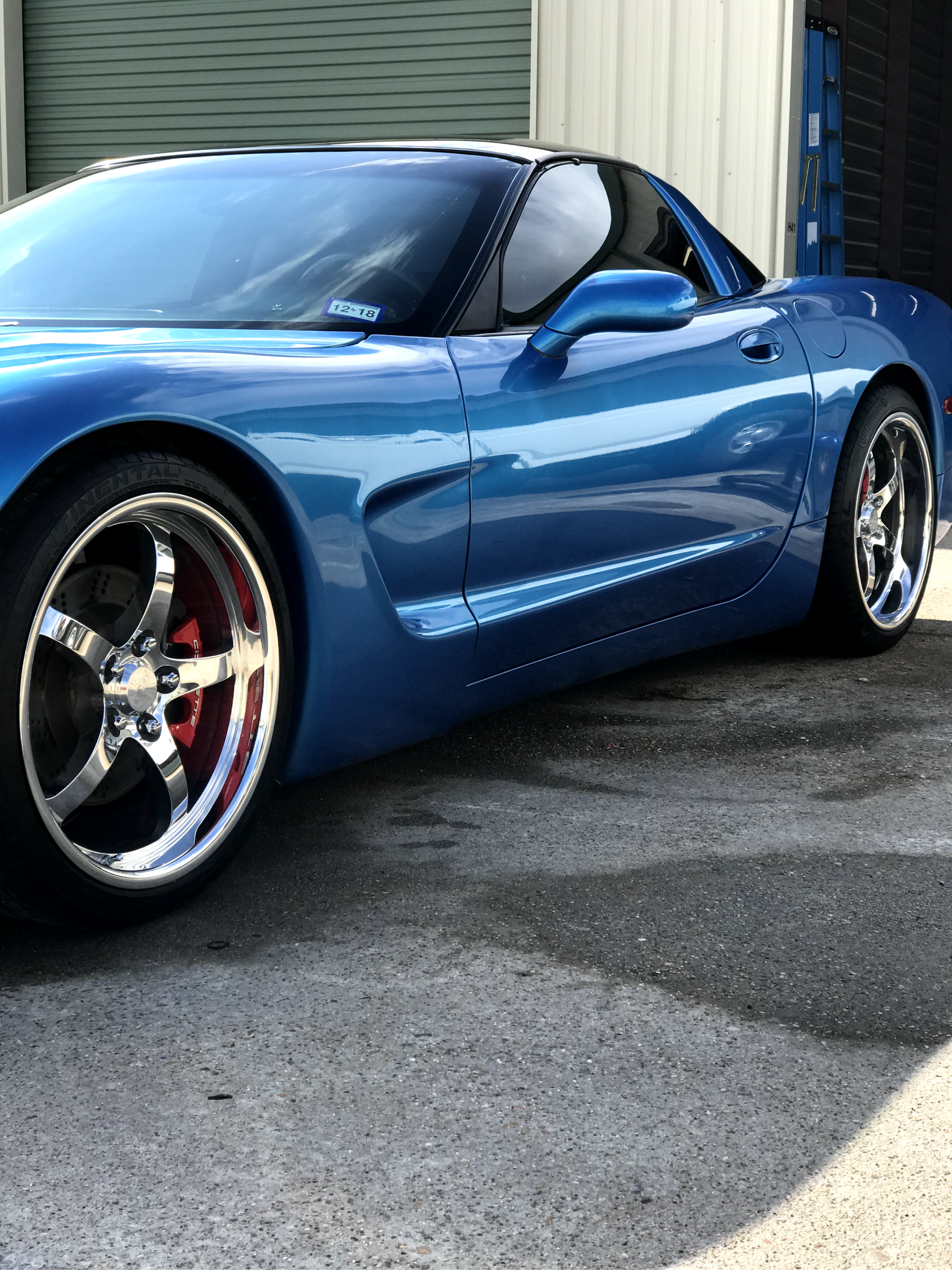 A blue sports car is parked in front of a garage door