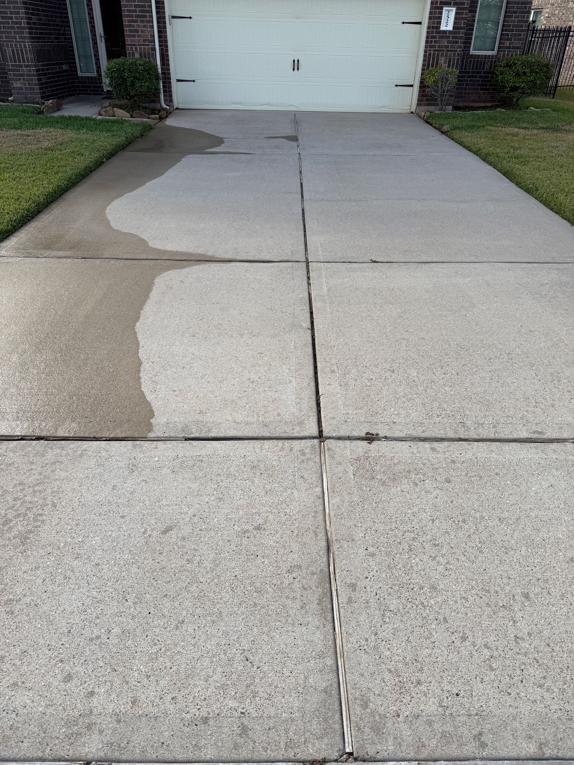 Driveway with water stain and grass on either side leading to a garage door.