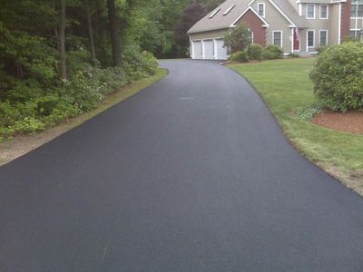 A driveway leading to a house with a lush green lawn.