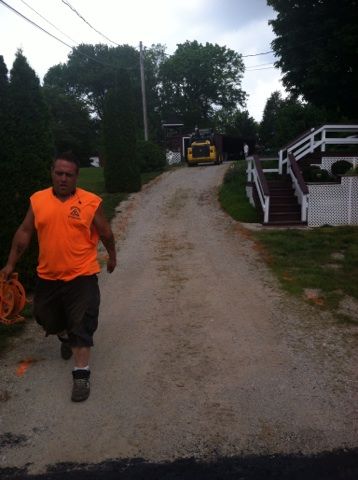 A man in an orange vest is walking down a dirt road