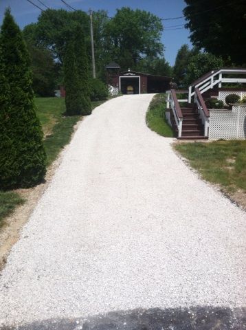 A gravel driveway leading to a house with stairs