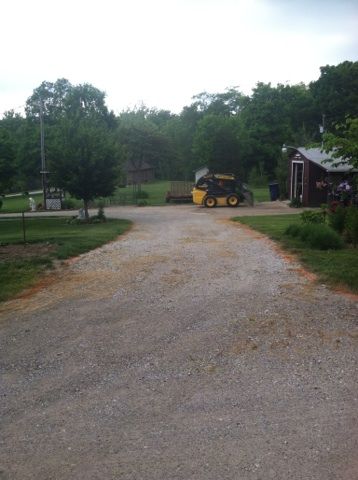 A yellow tractor is parked on the side of a gravel road.