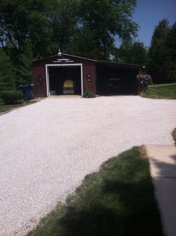 A red garage with a white gravel driveway leading to it