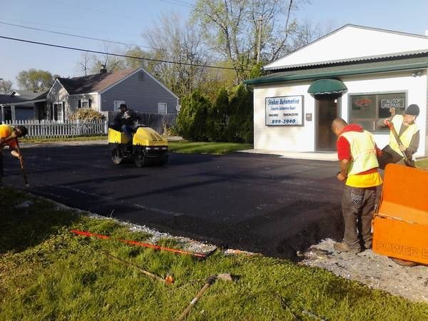 A group of men are working on a driveway in front of a building