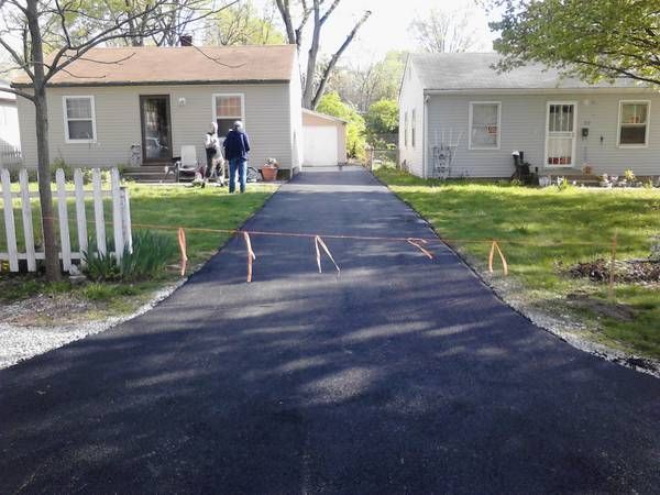 A driveway leading to a house with a white picket fence
