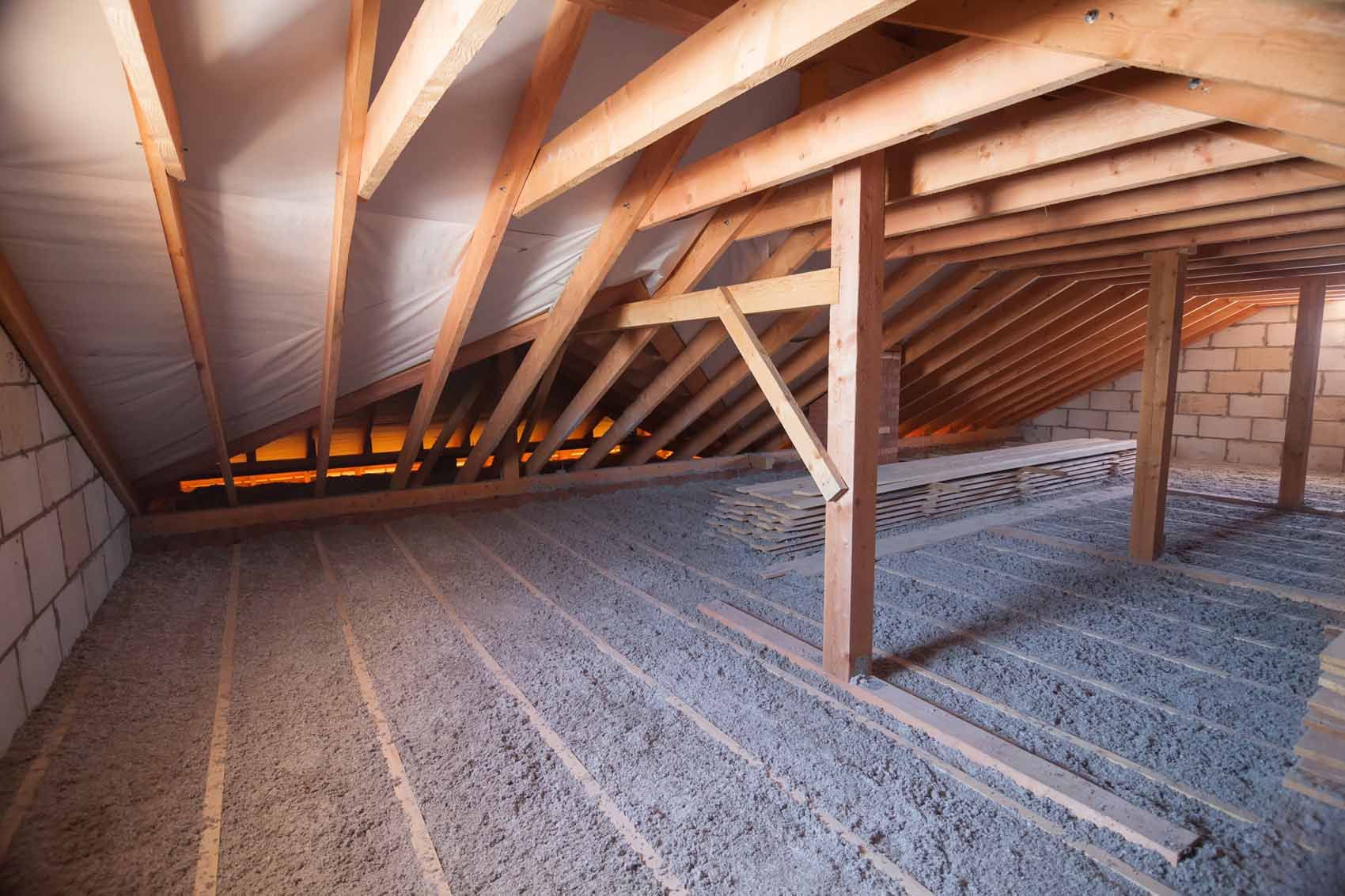 An empty attic with wooden beams and insulation.