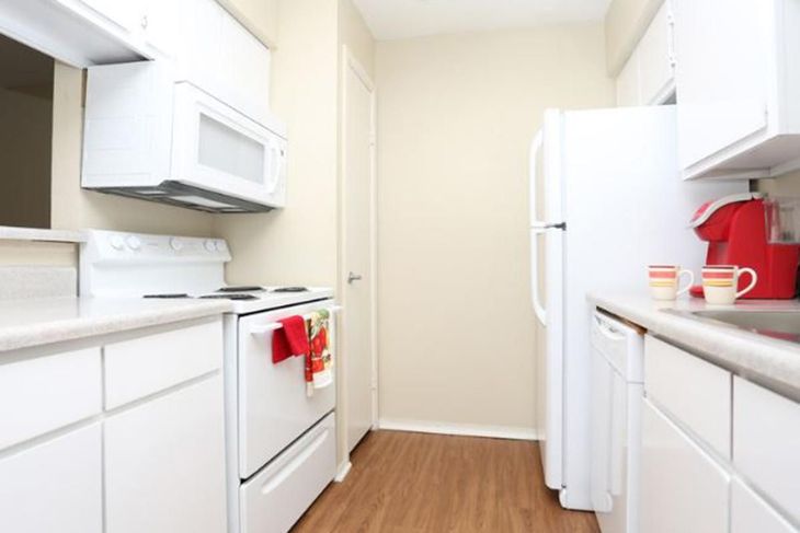 White kitchen with appliances: stove, microwave, refrigerator, cabinets, and coffee maker.