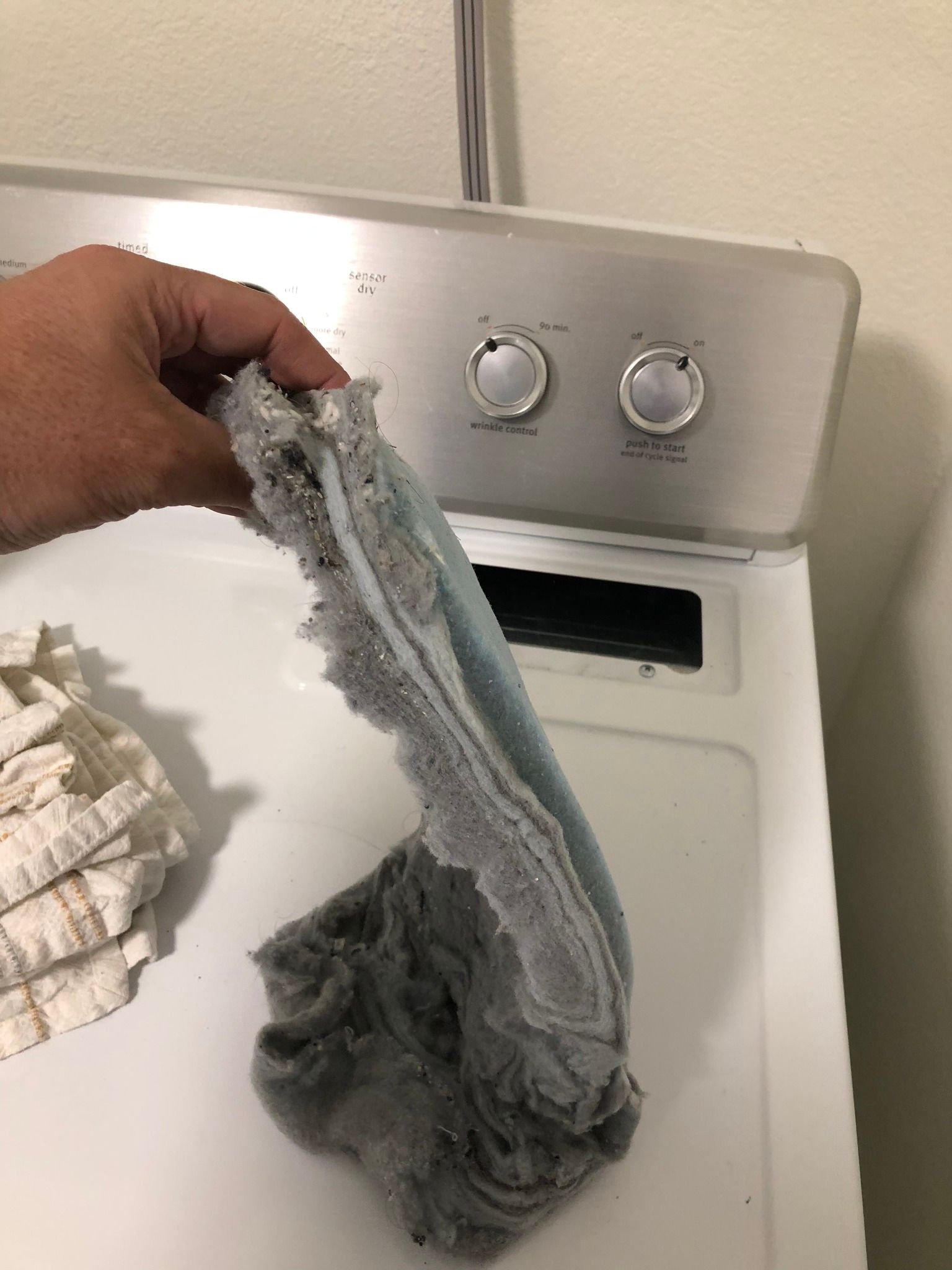 A person is holding a mop over a washing machine.