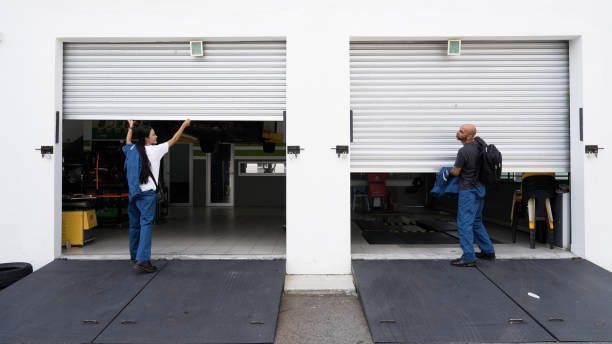 Two men are working on a garage door.