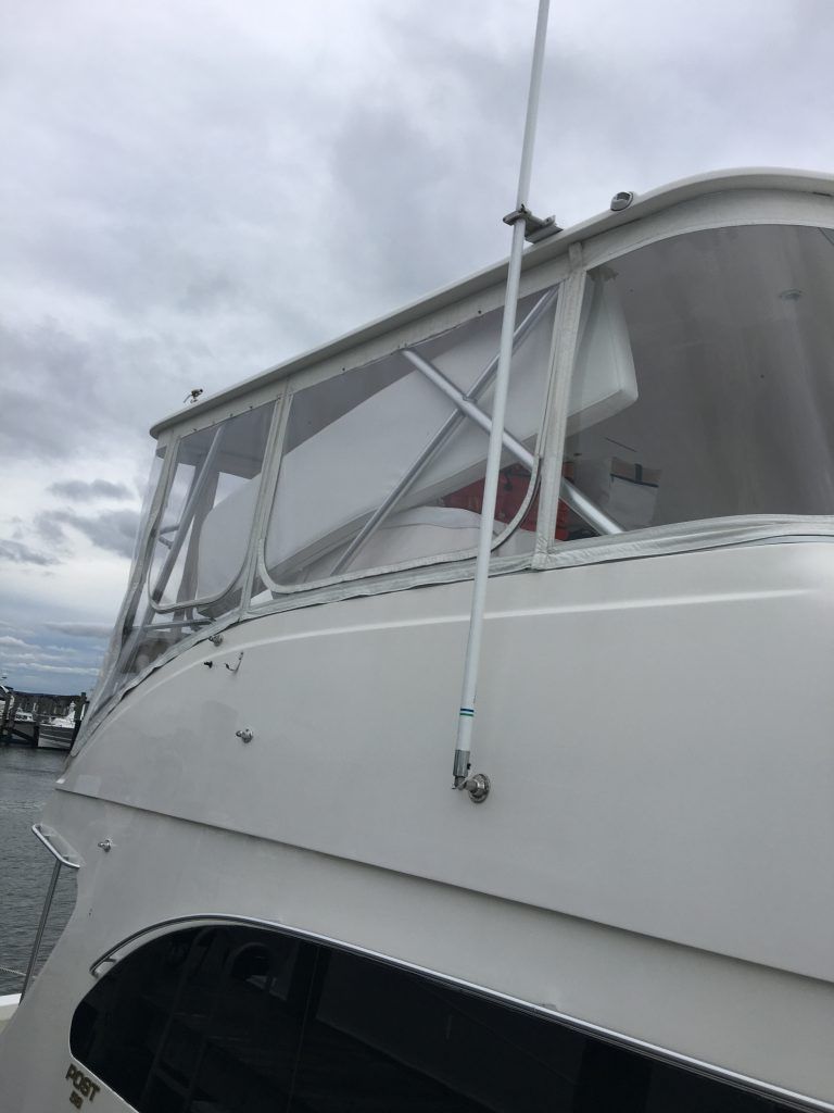 A white boat with a antenna on the side of it.